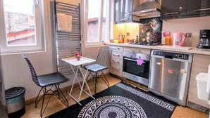 A compact kitchen with a dishwasher, oven, and a small dining area with a table and chairs. - Gorgeous Two Bedroom Apartment in Taksim - 3AC (Istanbul)