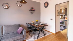 A modern living room with a grey sofa, a wooden dining table with chairs, and decorative wall shelves. - Gorgeous Two Bedroom Apartment in Taksim - 3AC (Istanbul)