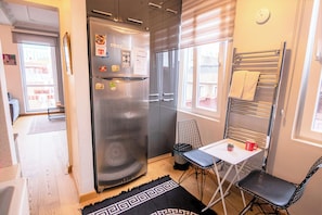 A compact kitchen with a stainless steel refrigerator, a small table with a chair, and a window with a towel rack. - Gorgeous Two Bedroom Apartment in Taksim - 3AC (Istanbul)