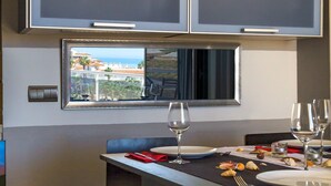 Un coin repas avec une table dressée pour deux personnes, une fenêtre offrant une belle vue et un téléviseur à écran plat fixé au-dessus de la table.