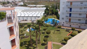 Un quartier résidentiel doté d’une piscine, de palmiers et offrant une vue sur un paysage vallonné.