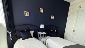 Une chambre double avec deux lits, une table de chevet avec une lampe et une armoire.