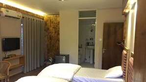 A hotel room with two beds, a TV, a desk, and a bathroom visible through an open door. - Silu Homes (Lalitpur)