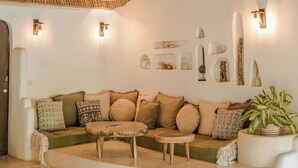 A room with a woven ceiling, a sofa set, a coffee table, wall-mounted lights, and a potted plant. - Mana Earthly Paradise (Ubud)