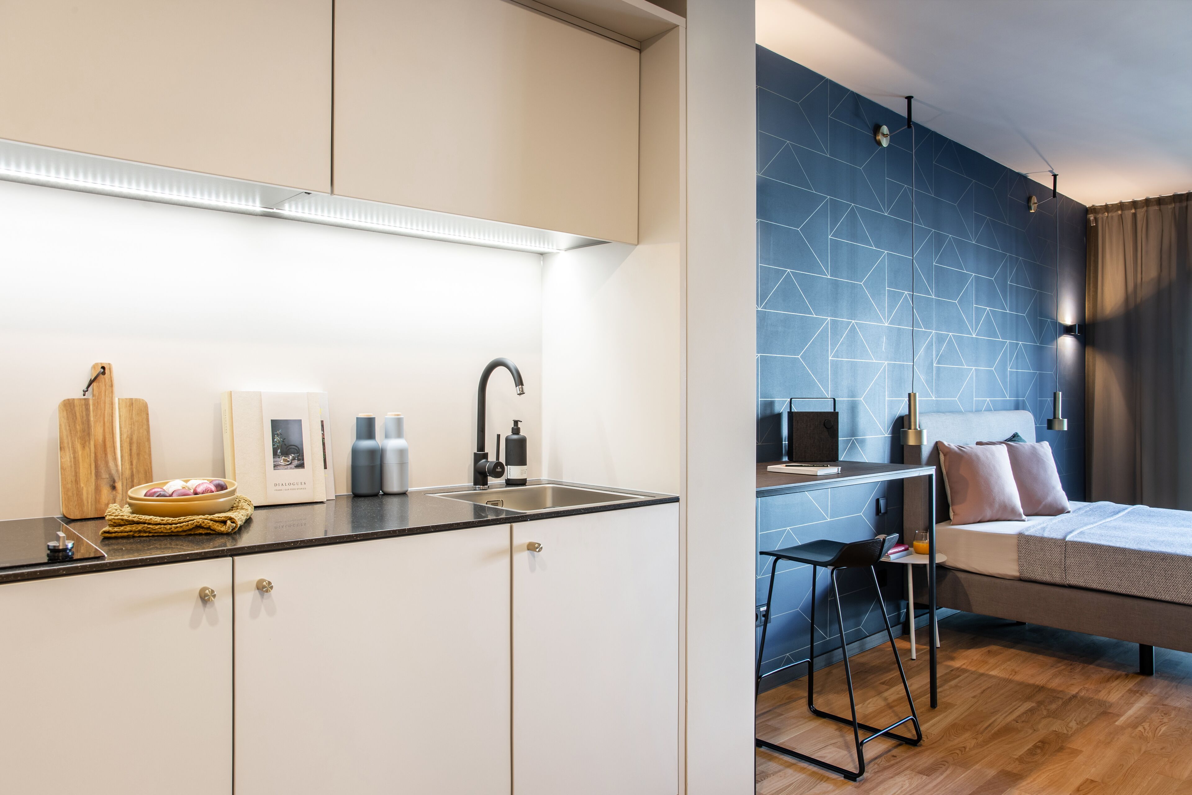 A modern kitchen with a black countertop, white cabinets, and a wooden cutting board.