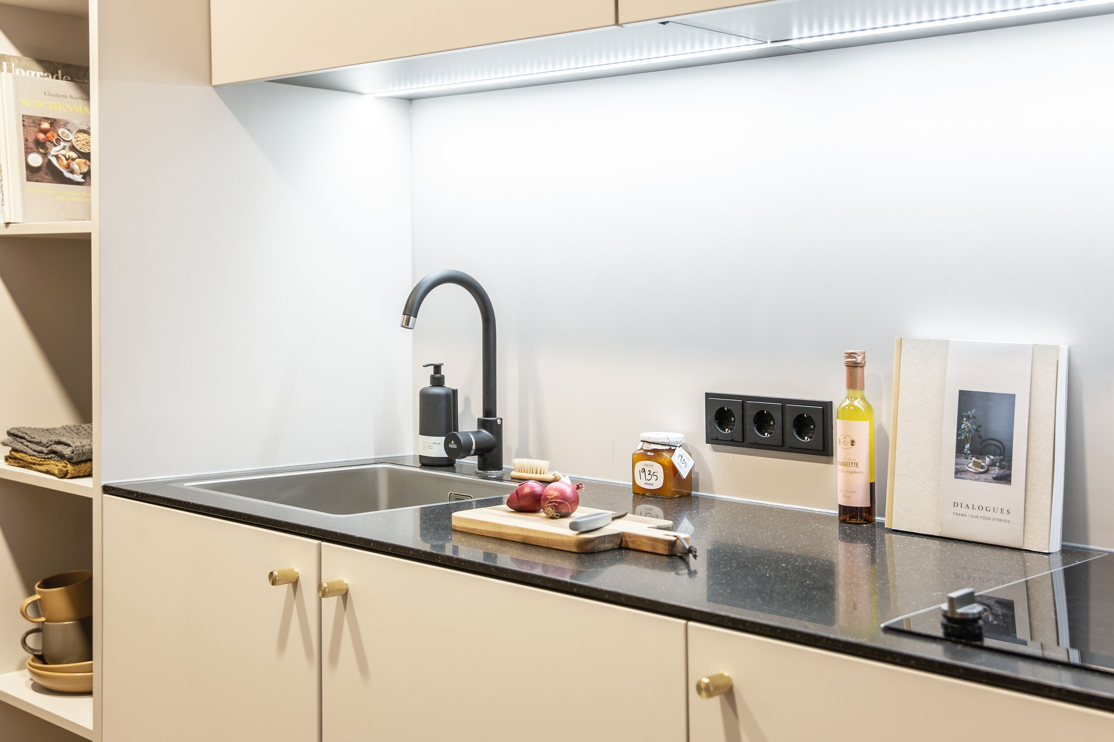 Een moderne keuken met een zwart aanrecht, een spoelbak en een fles wijn.