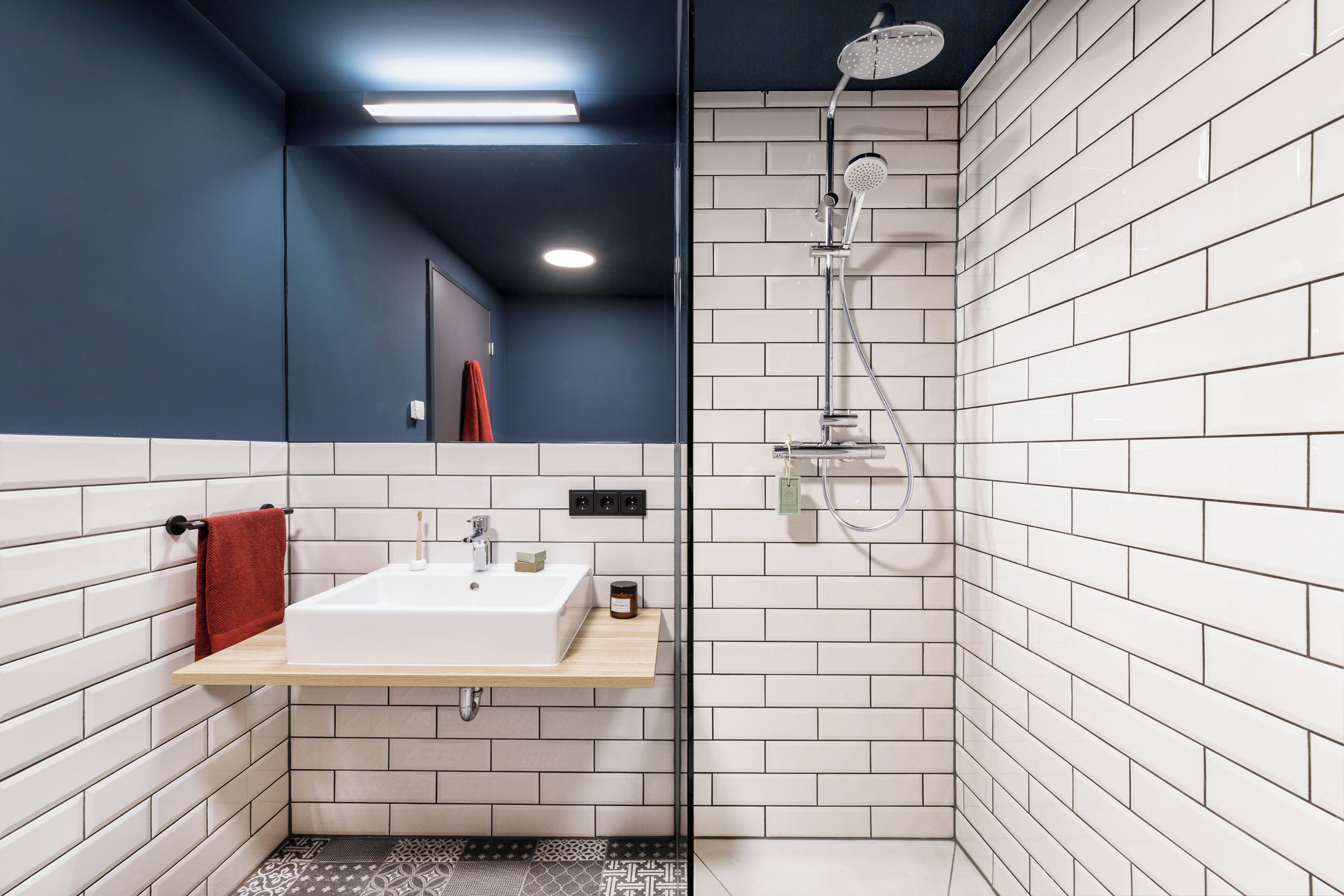 Un baño moderno con un lavabo blanco, una toalla roja y una ducha.