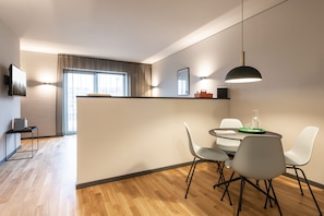 A modern dining area with a round table, white chairs, and a pendant light.