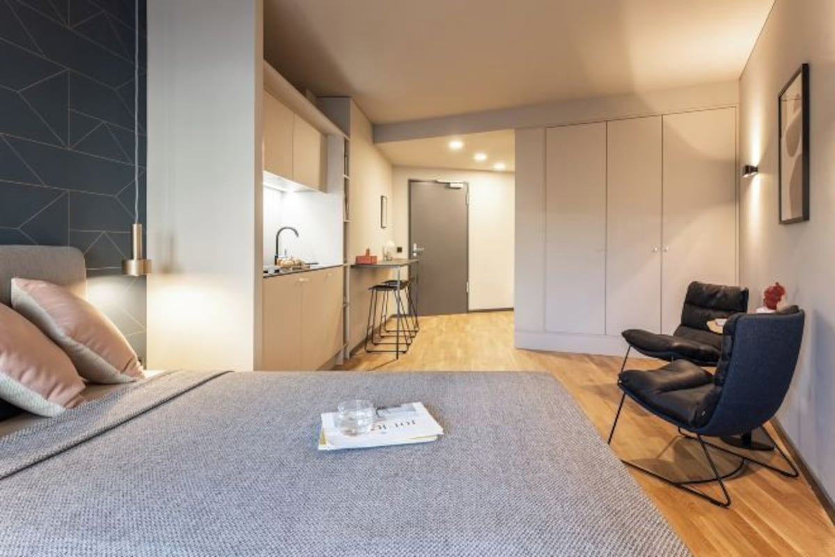 A modern bedroom with a bed, a reading area with a magazine, a desk, and a chair.
