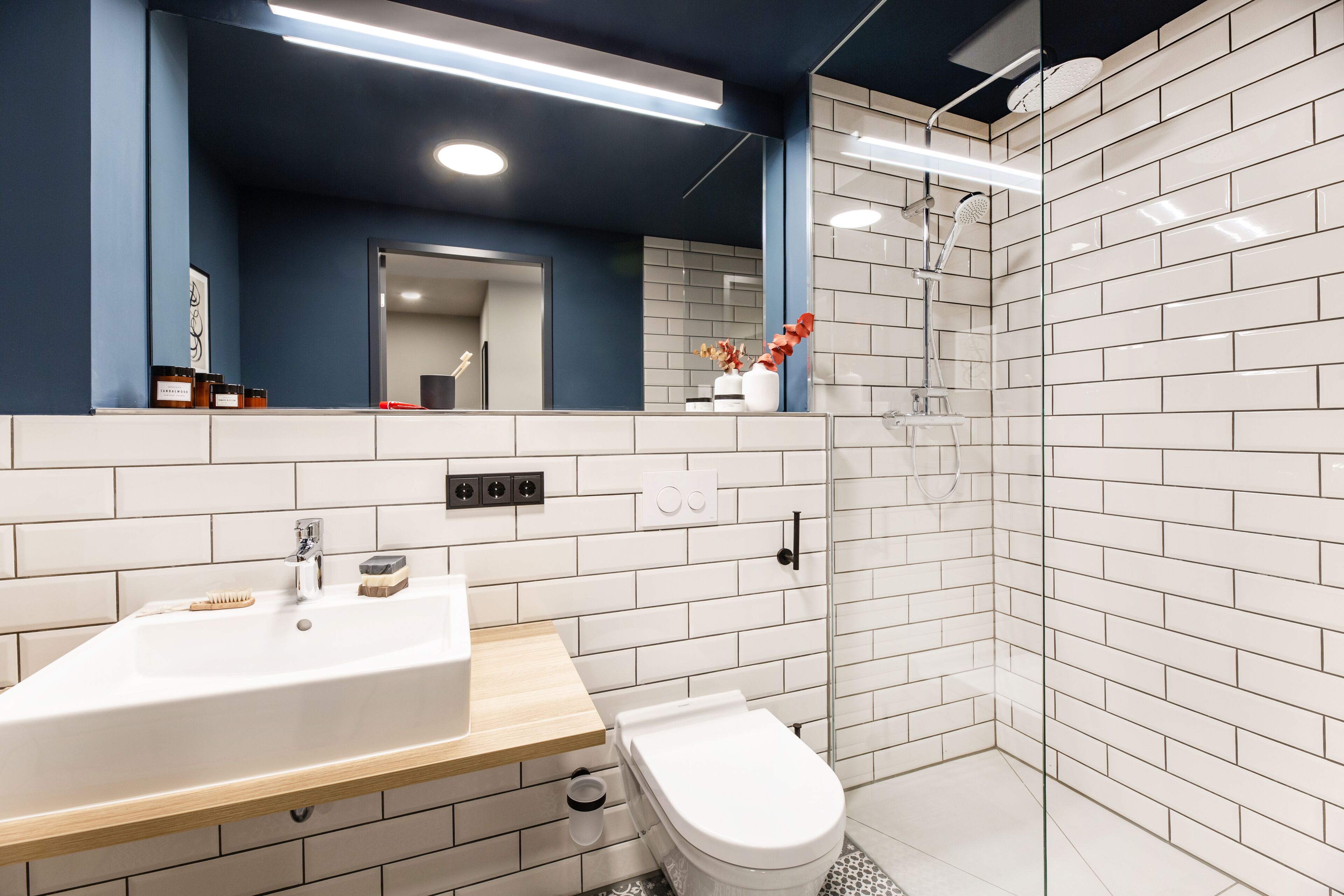 Een moderne badkamer met een wit wastafel, een houten aanrechtblad en een douchecabine met glazen wanden.