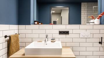 A bathroom with a white sink, wooden countertop, and a towel hanging on a rack.