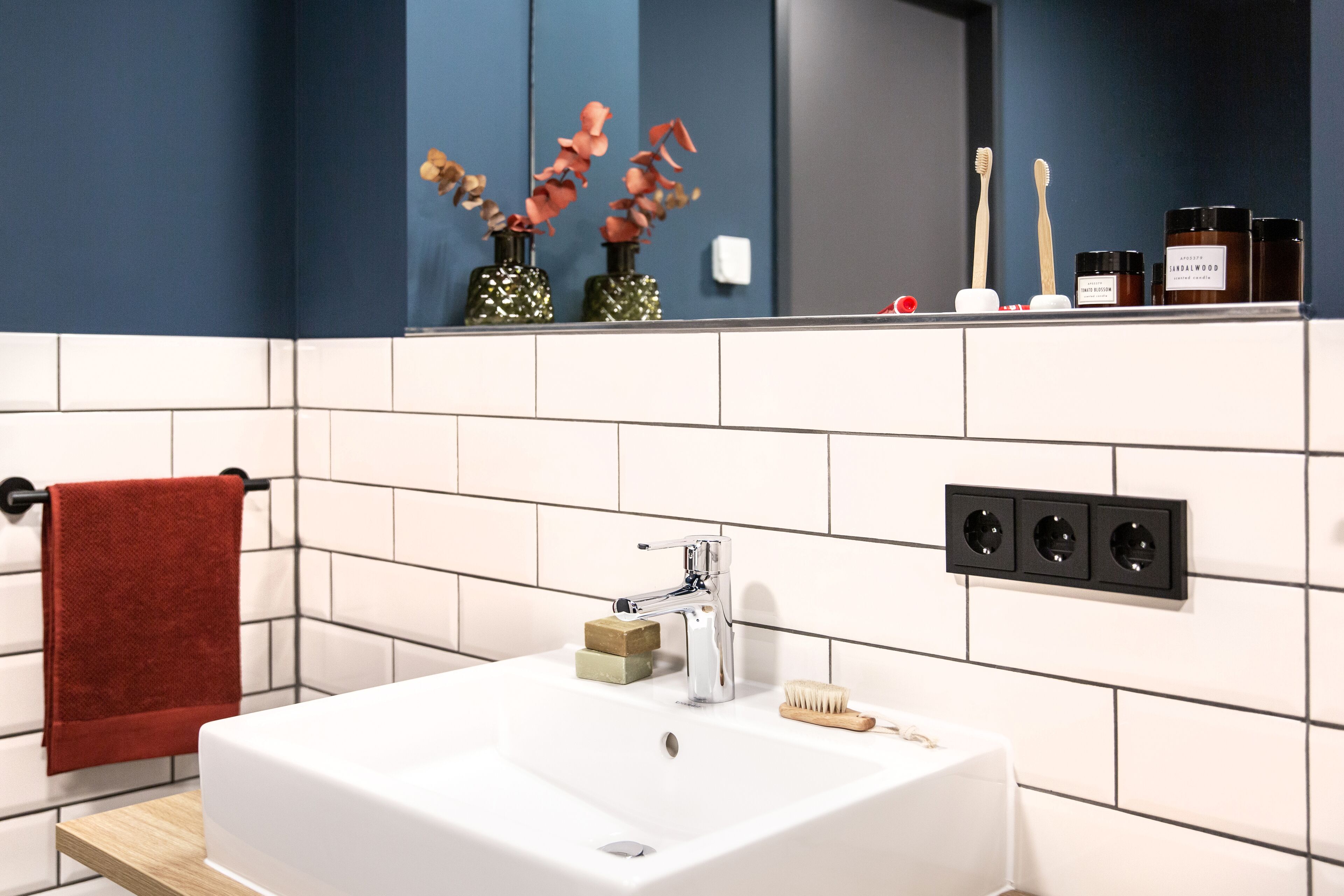A bathroom with a white sink, a red towel, and a mirror above the sink.