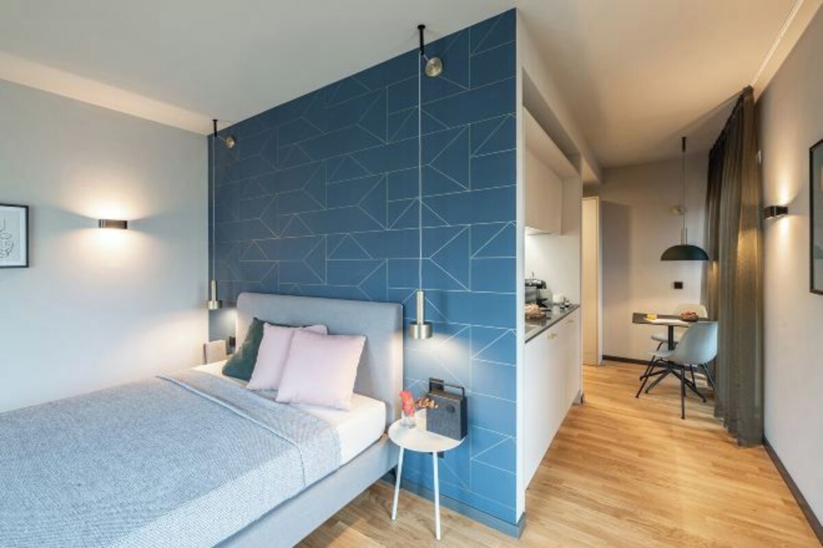 A modern bedroom with a bed, bedside table, and a blue accent wall.