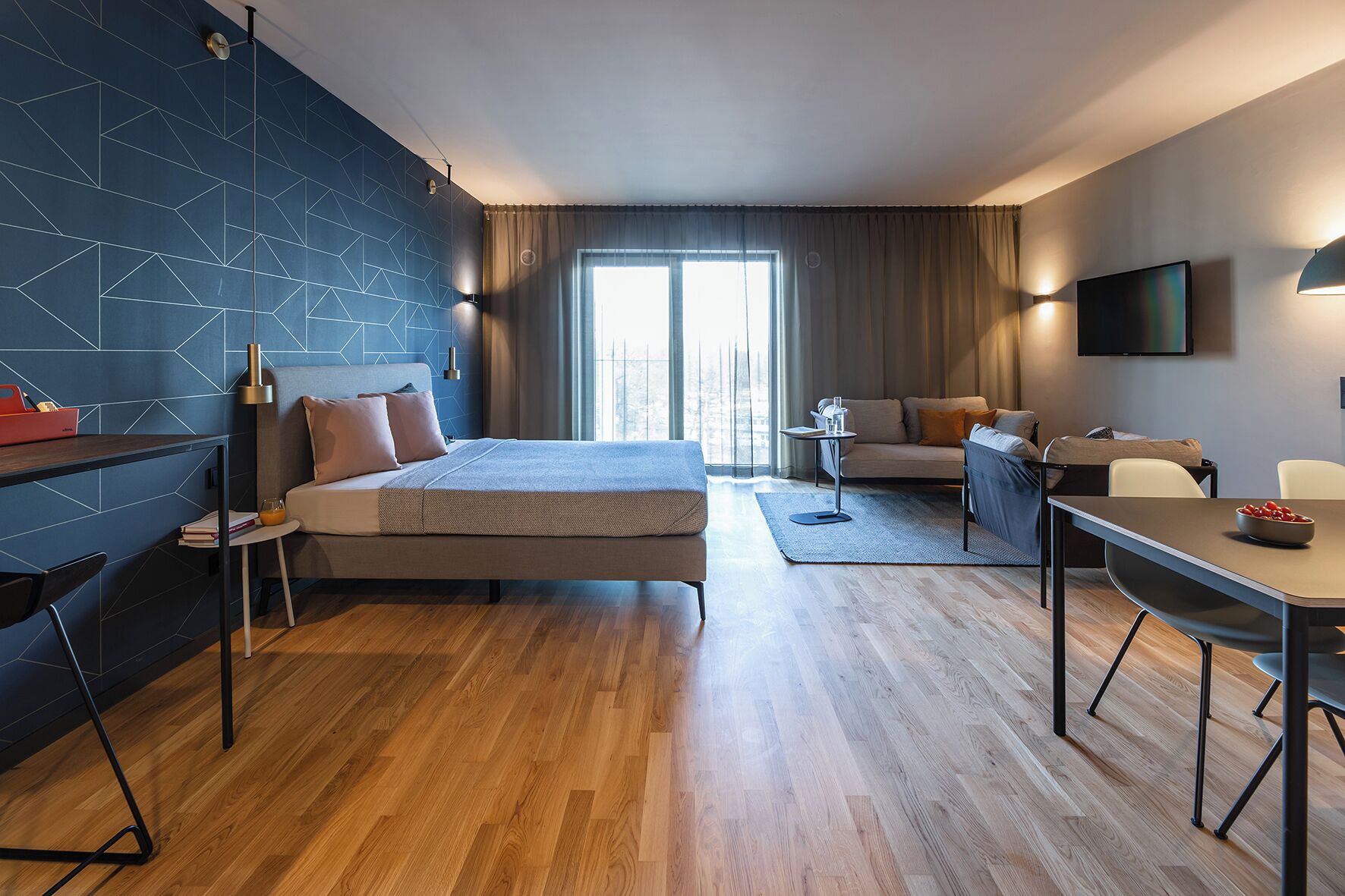 Una habitación de hotel moderna con una cama grande, un sofá, un escritorio y un televisor.