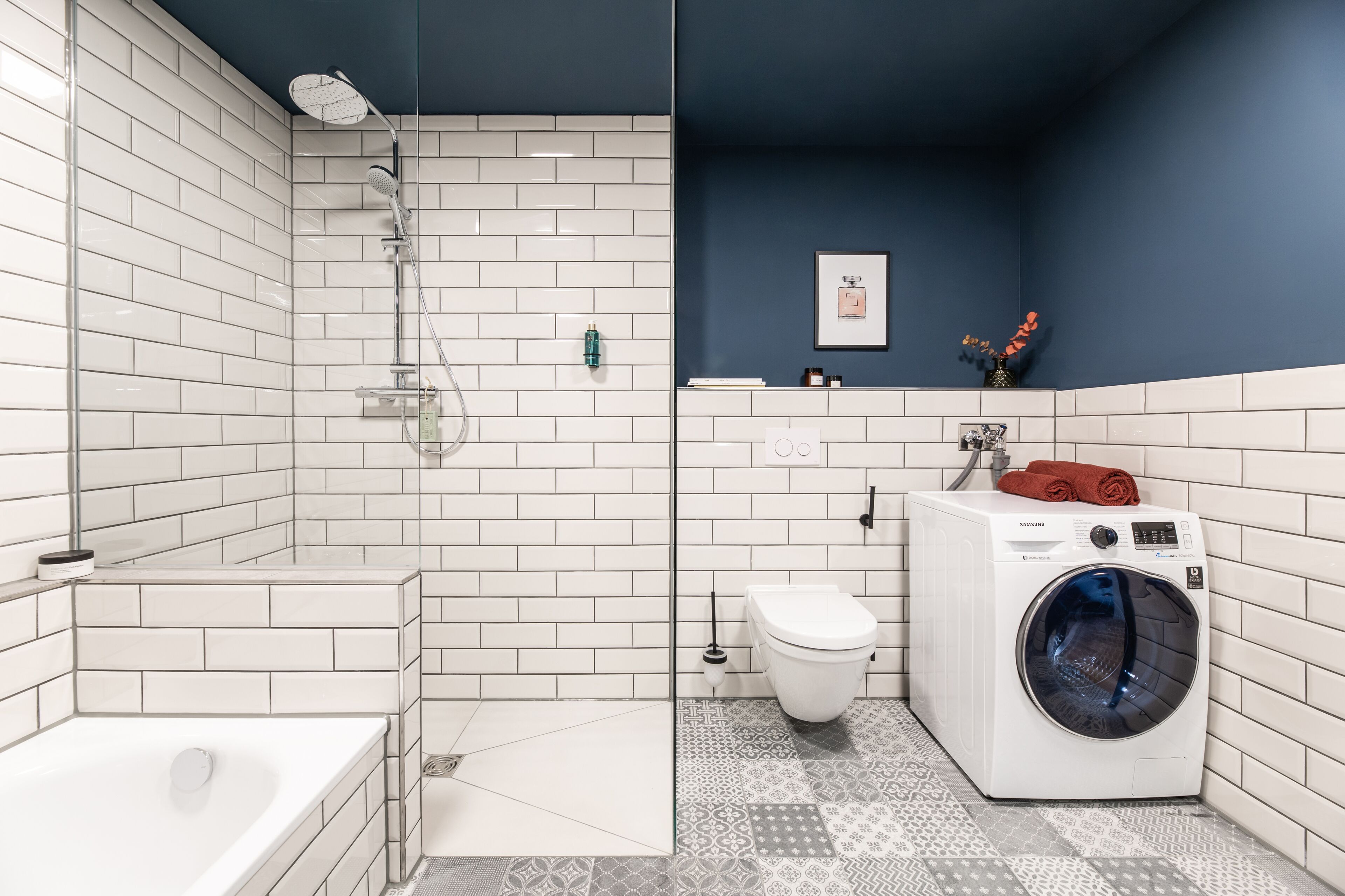 A modern bathroom with a bathtub, shower, toilet, and a washing machine.