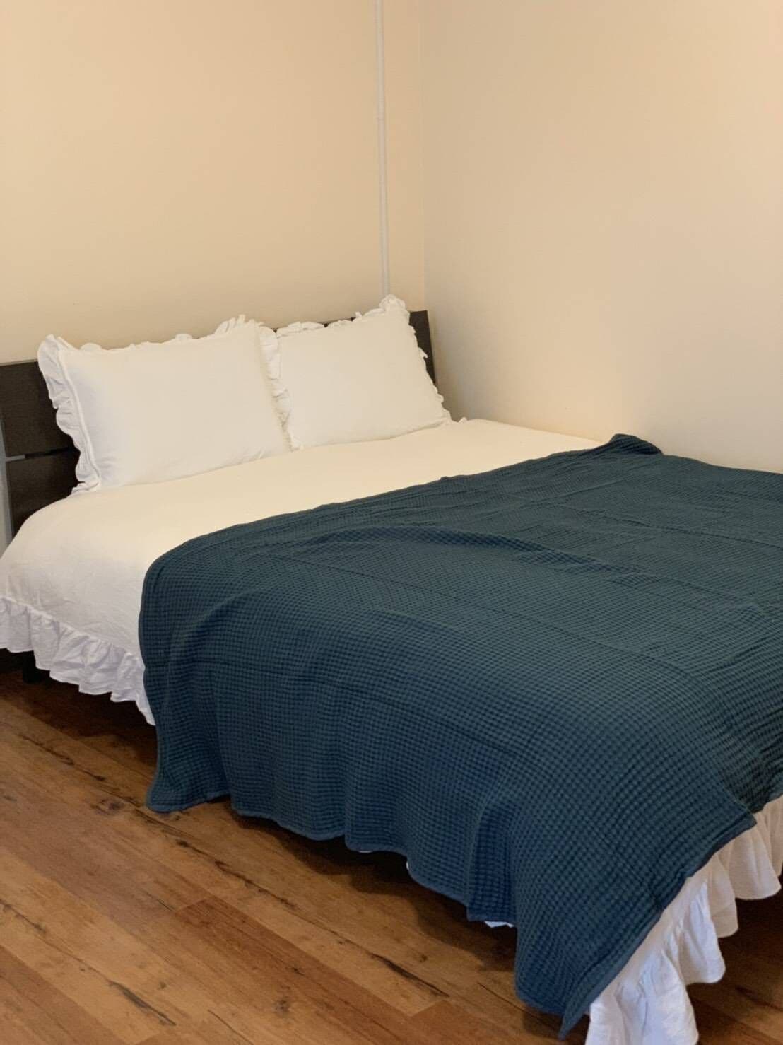 A bed with white bedding and a teal blanket.