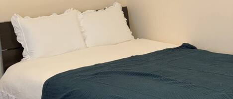 A bed with white bedding and a teal blanket.