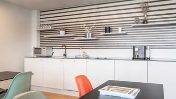 Une cuisine moderne avec un motif rayé sur les murs, des meubles blancs et un coin repas comprenant une table et des chaises.