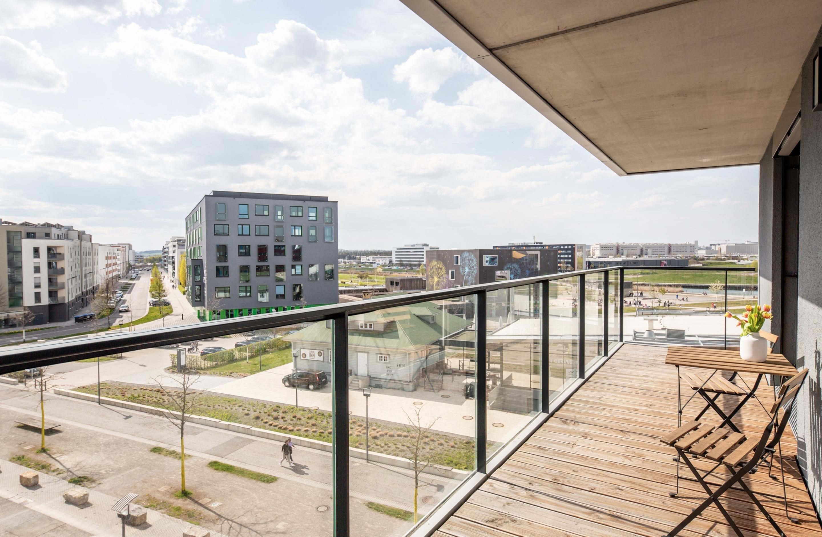 Un balcón con vistas a un paisaje urbano, que incluye edificios modernos y una carretera.