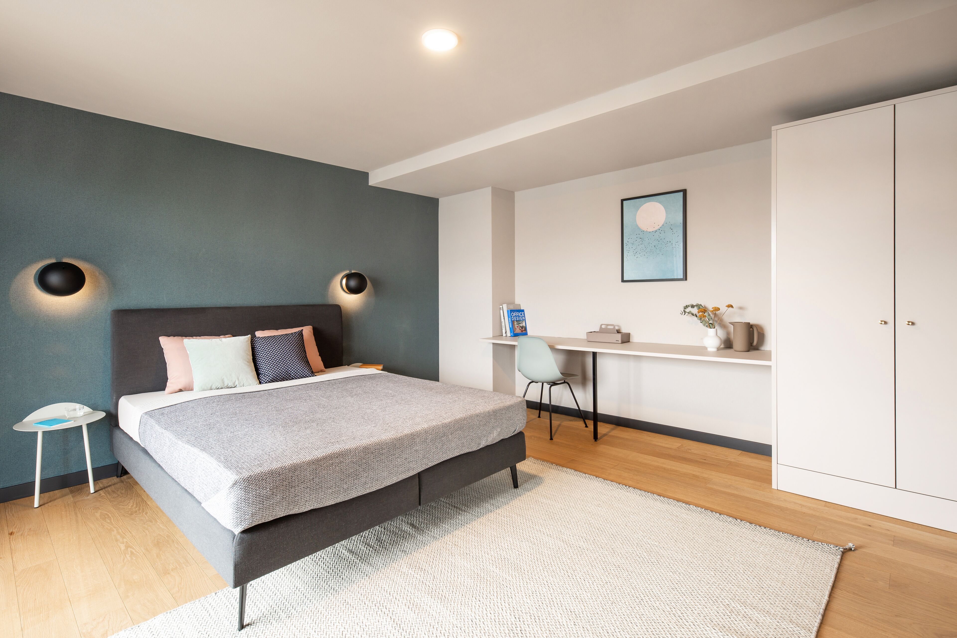 Un dormitorio moderno con cama, mesitas de noche, escritorio y armario.