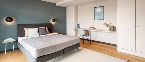 A modern bedroom with a bed, bedside tables, a desk, and a wardrobe.