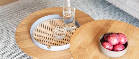 Una mesa redonda de madera con una botella y un cuenco de fruta.