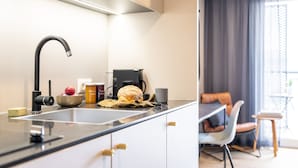 A modern kitchen with a black faucet, a coffee maker, and a loaf of bread on the counter. - ipartment Boeblingen @HOME by Best Western (Boeblingen)