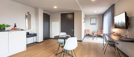 A modern hotel room with a dining area, a kitchen, and a living space.