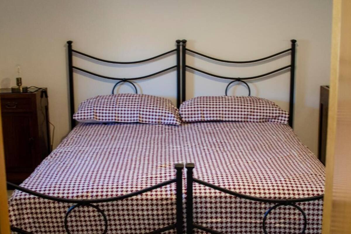A single bed with a metal frame and a checkered bedspread.