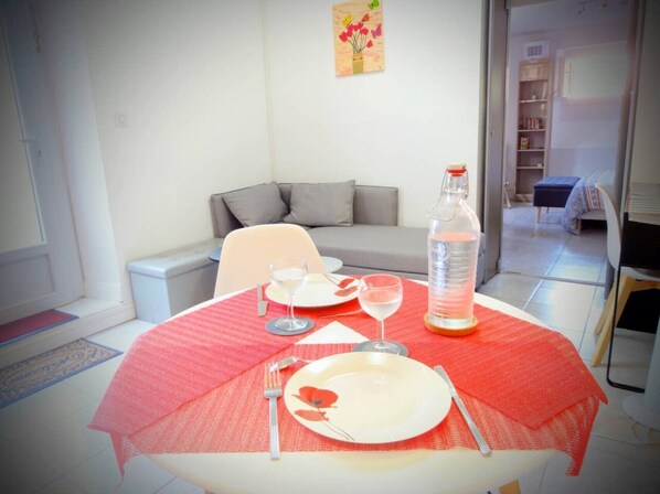 A dining area with a table set for two, a water bottle, and a painting on the wall.