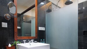 Ein modernes Badezimmer mit einem großen Spiegel, einem weißen Waschbecken und einer Duschkabine.