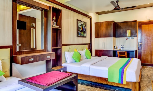 A hotel room with a bed, bedside table, a mirror, a wardrobe, a desk with a chair, and a ceiling fan. - Itsy Hotels The Villa Retreat (Siliguri)