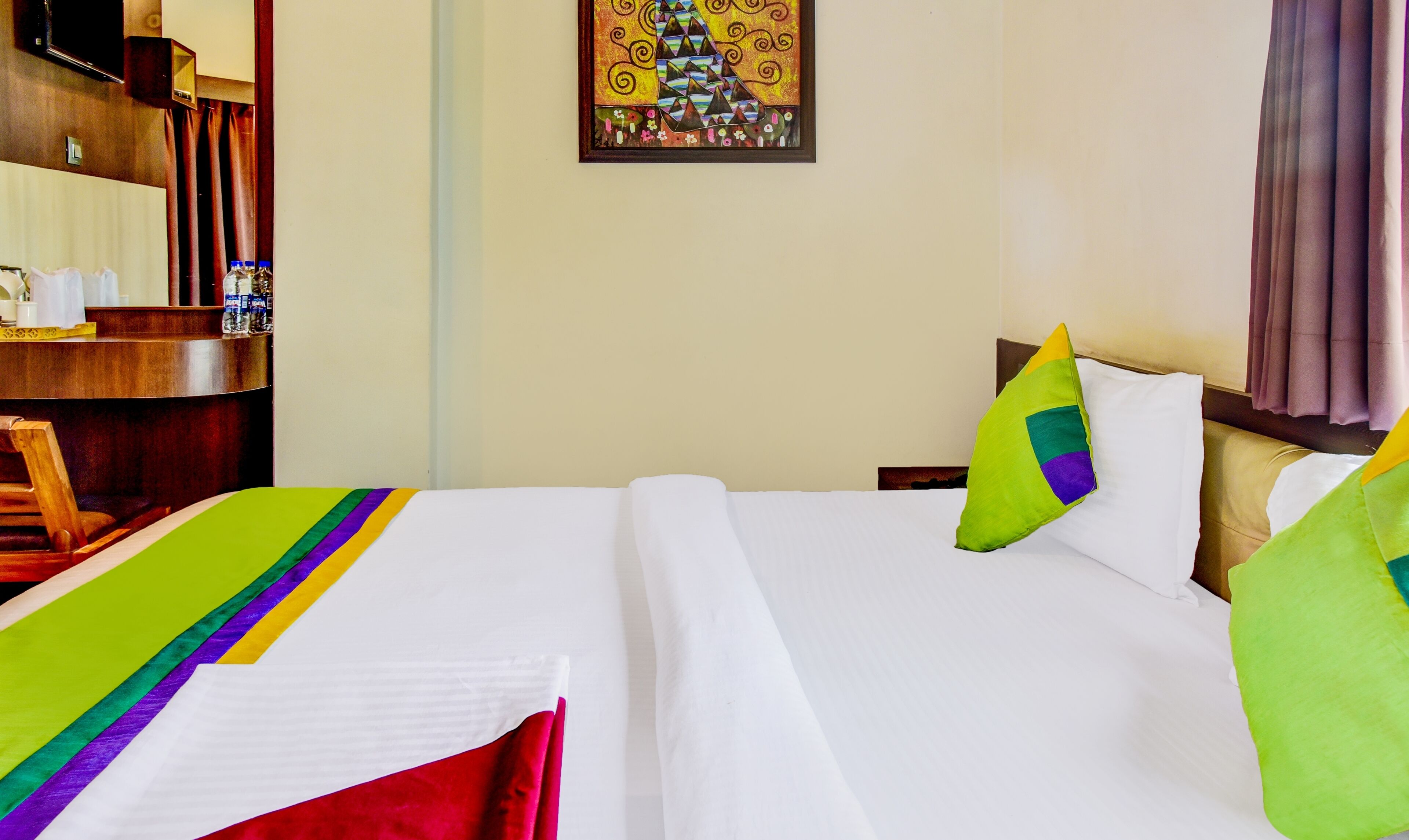 Una habitación de hotel con una cama, un escritorio y un cuadro en la pared.