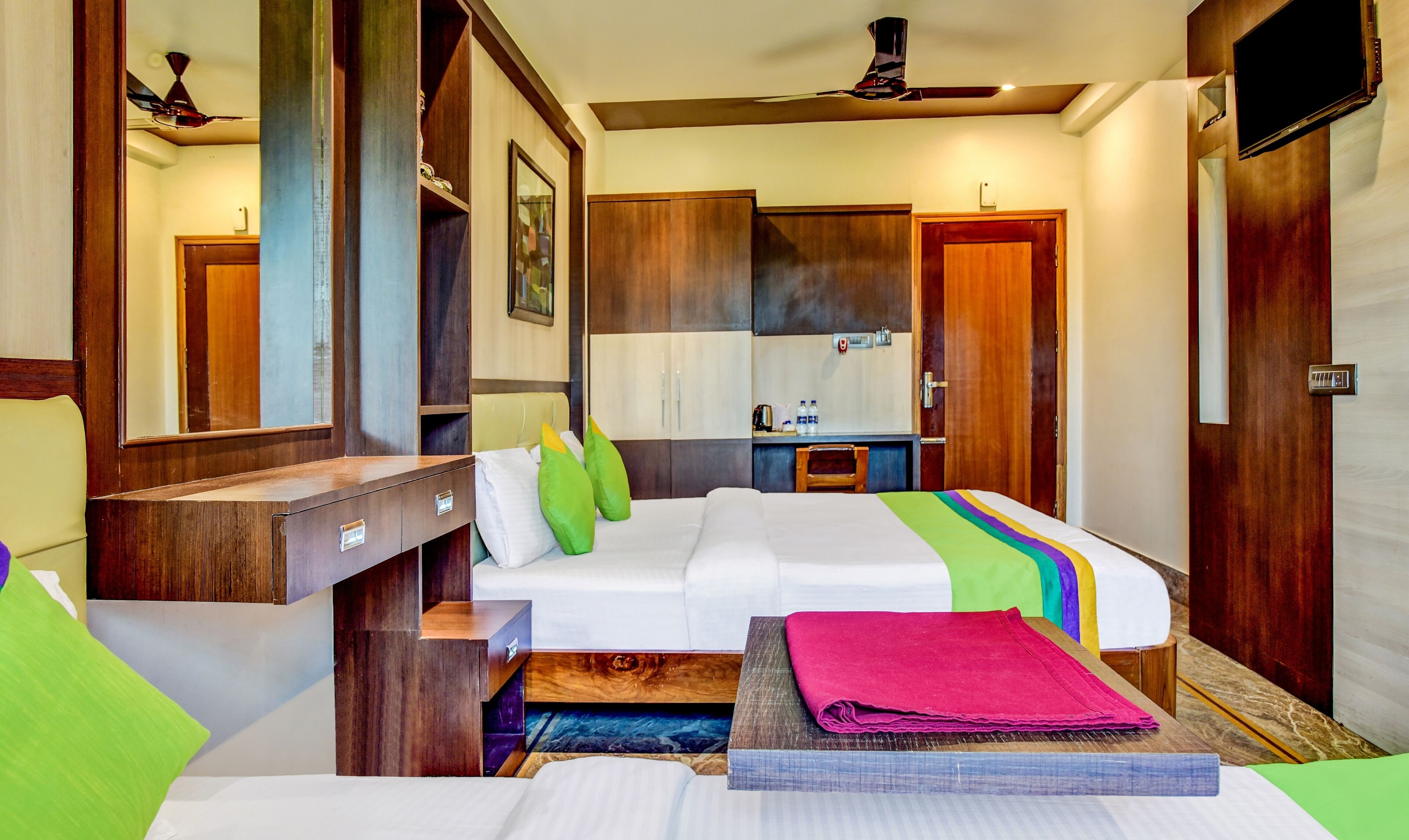 Una habitación de hotel con cama, escritorio, silla, armario y televisor.