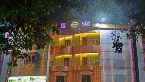 Un edificio con varios balcones, luces colgantes y letreros que dicen 'The Family Bar & Kitchen' y 'Gujarat Motel'.