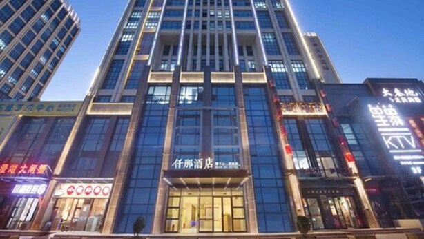 A modern hotel with a prominent entrance, large windows, and a well-lit facade.