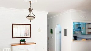 Un coin repas avec une table et des chaises en bois, un buffet blanc et un luminaire suspendu.