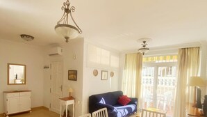 Un coin repas avec une table en bois et des chaises blanches, un canapé bleu et un lustre.
