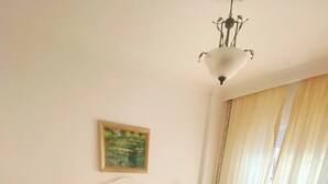 Une chambre d’hôtel avec un lit, deux tables de chevet avec des lampes, un tableau au mur et une fenêtre avec des rideaux.
