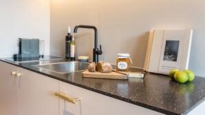 A kitchen with a black countertop, a sink, a cutting board with bread and a honey jar, and a book titled 'Dialogues'.