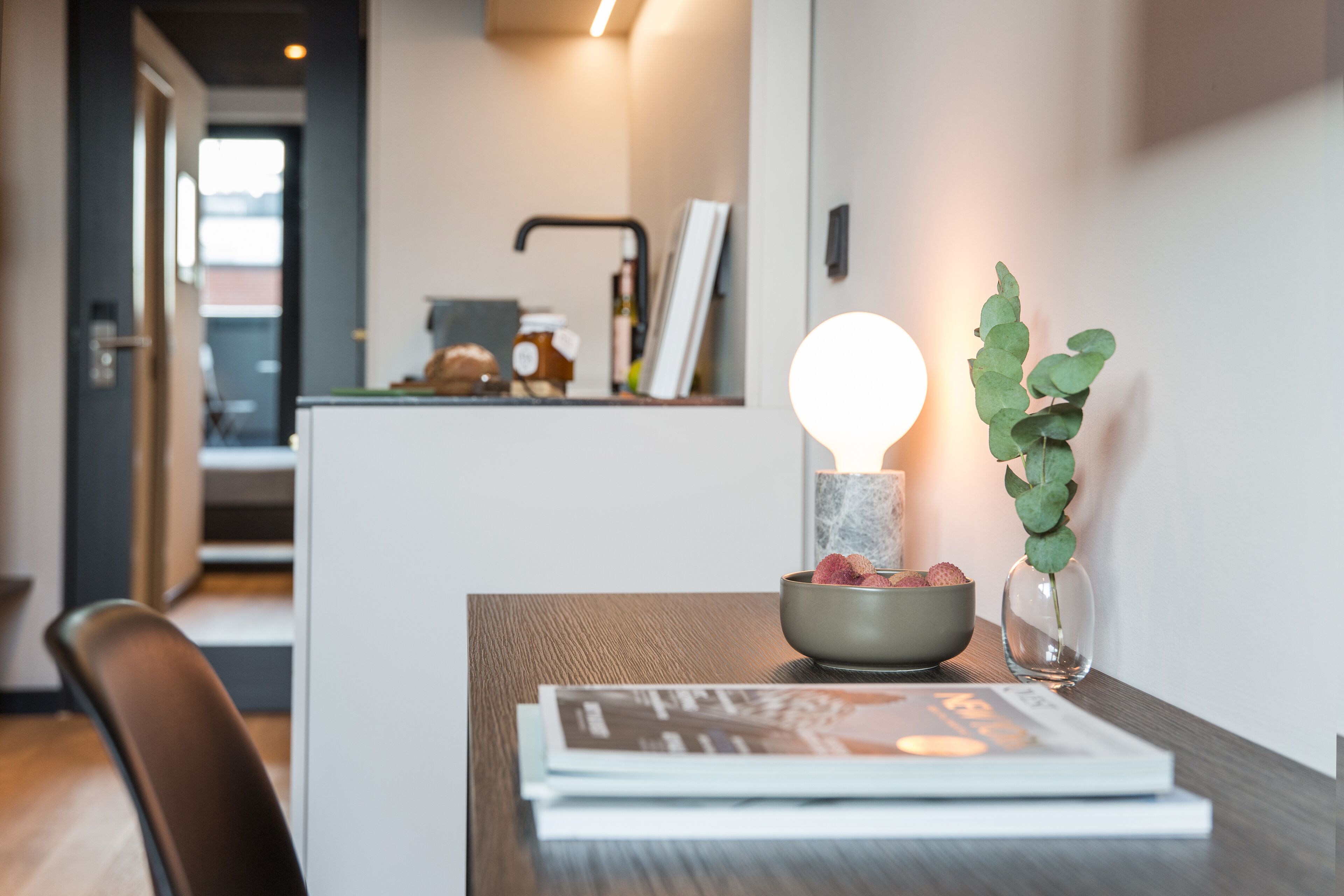 Una cocina moderna con una zona de comedor. Hay un bol con una vela y una planta sobre la mesa.