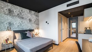 A modern bedroom with a large bed, bedside tables, a desk, and a view into another room.