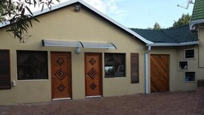 A building with two symmetrical doors, a small window, and a covered entrance. - Northwold Comfort Living (Randburg)