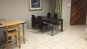 A dining area with a table and chairs, a framed picture on the wall, and a door with a patterned design. - Northwold Comfort Living (Randburg)