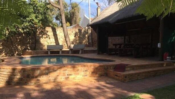A backyard with a swimming pool, a barbecue area, and a covered seating area. - Northwold Comfort Living (Randburg)