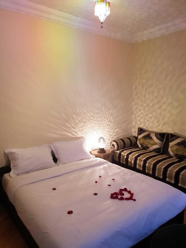 A hotel room with a bed, pillows, a bedside lamp, and a decorative wall.