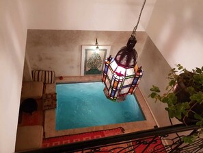 A small indoor swimming pool with a colorful hanging lantern above it.
