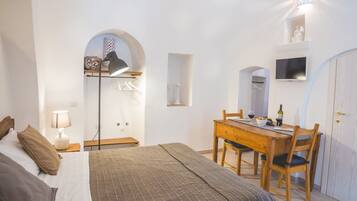 Une chambre à coucher comprenant un lit, une table de chevet, une lampe et une table à manger en bois avec des chaises.