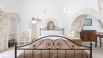 Een slaapkamer met een metalen bed, stenen muren en een rustieke uitstraling.