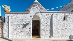 A white stone building with a conical roof, an arched entrance, and a small window. - Trullieu Guesthouse (Alberobello)